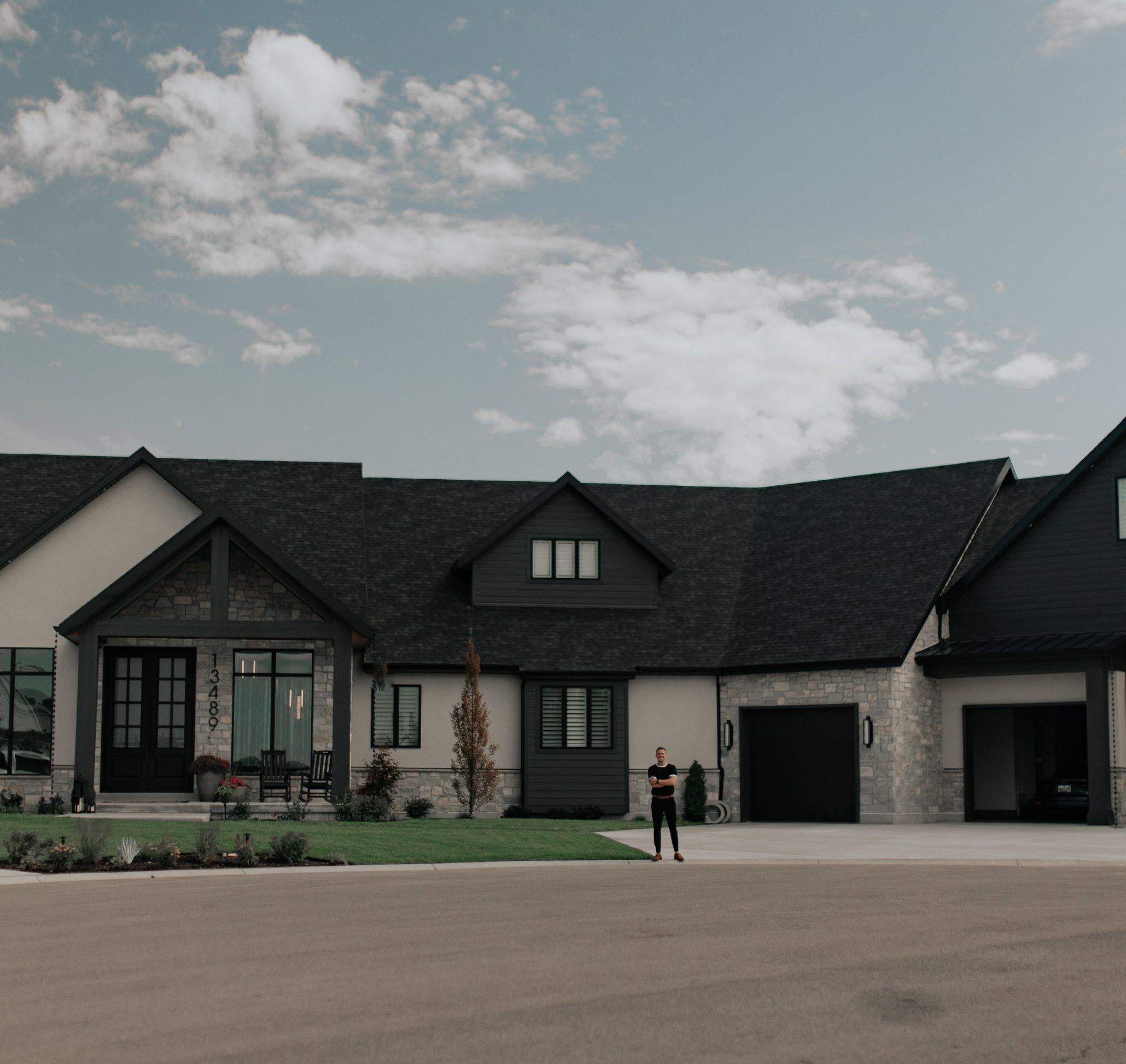 Conner standing arms crossed in front of a custom new construction home on the Wasatch Front